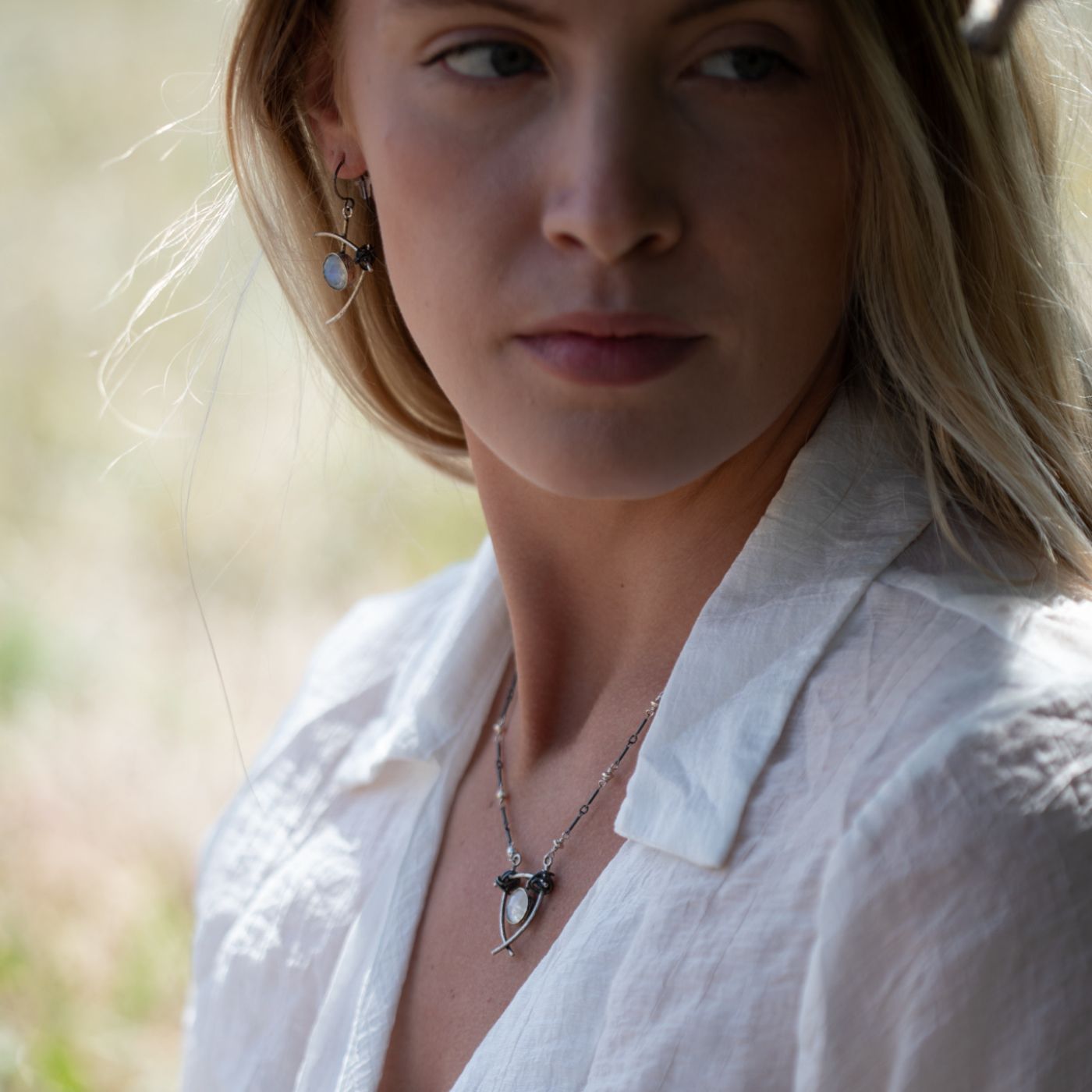 Model wearing nature-inspired handcrafted sterling silver jewelry in an outdoor setting, showcasing the elegance and artistry available at the Garden of Silver studio in West Hampton Beach.